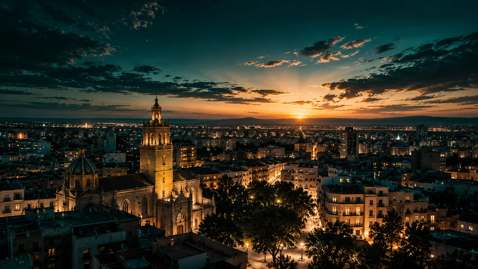 Vista de una ciudad al anochecer con la torre de una catedral iluminada, calles con farolas y el sol poniéndose sobre la llanura